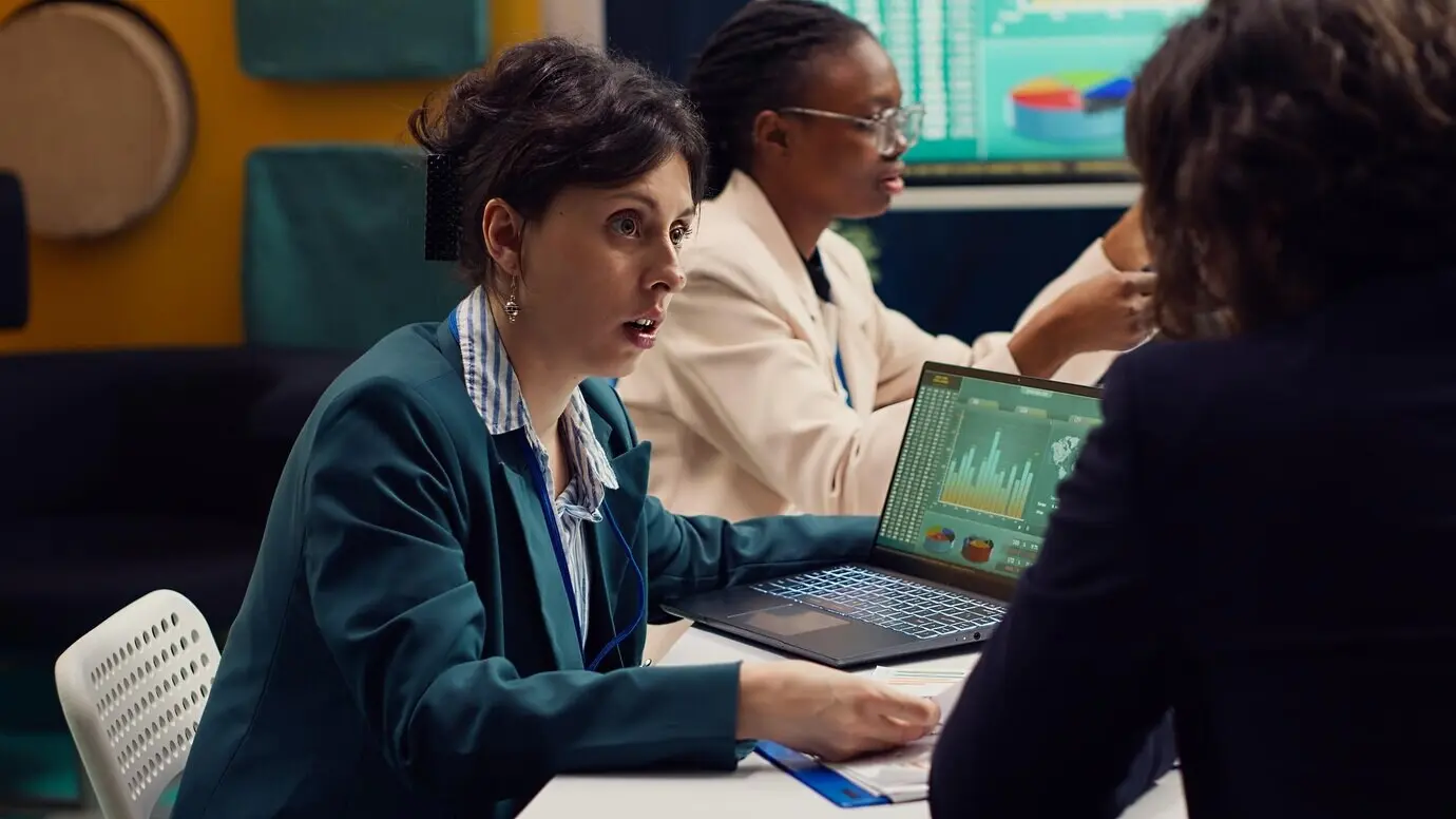 Команда стартапа изучает финансовые отчеты и показатели эффективности на ноутбуке.